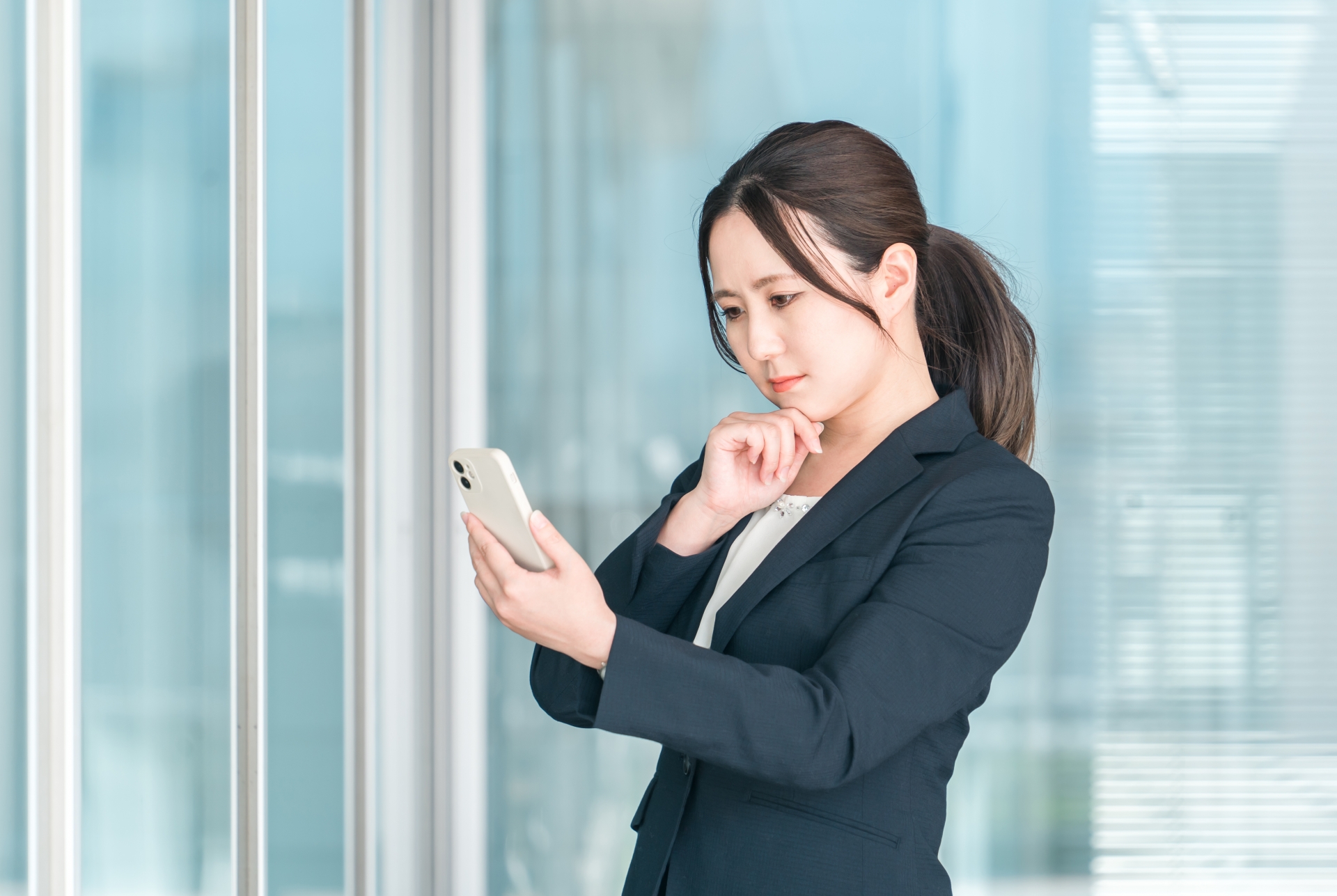 携帯電話を見ながら悩む女性