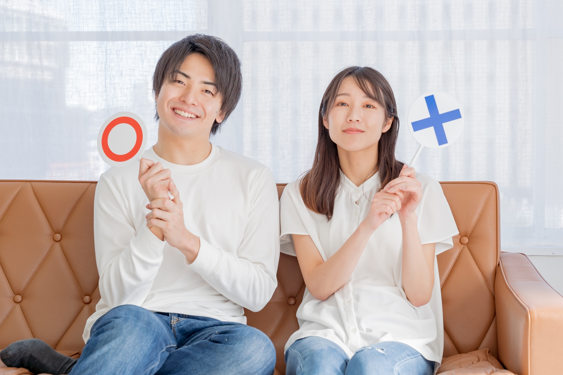 丸とバツの札を持つ男女