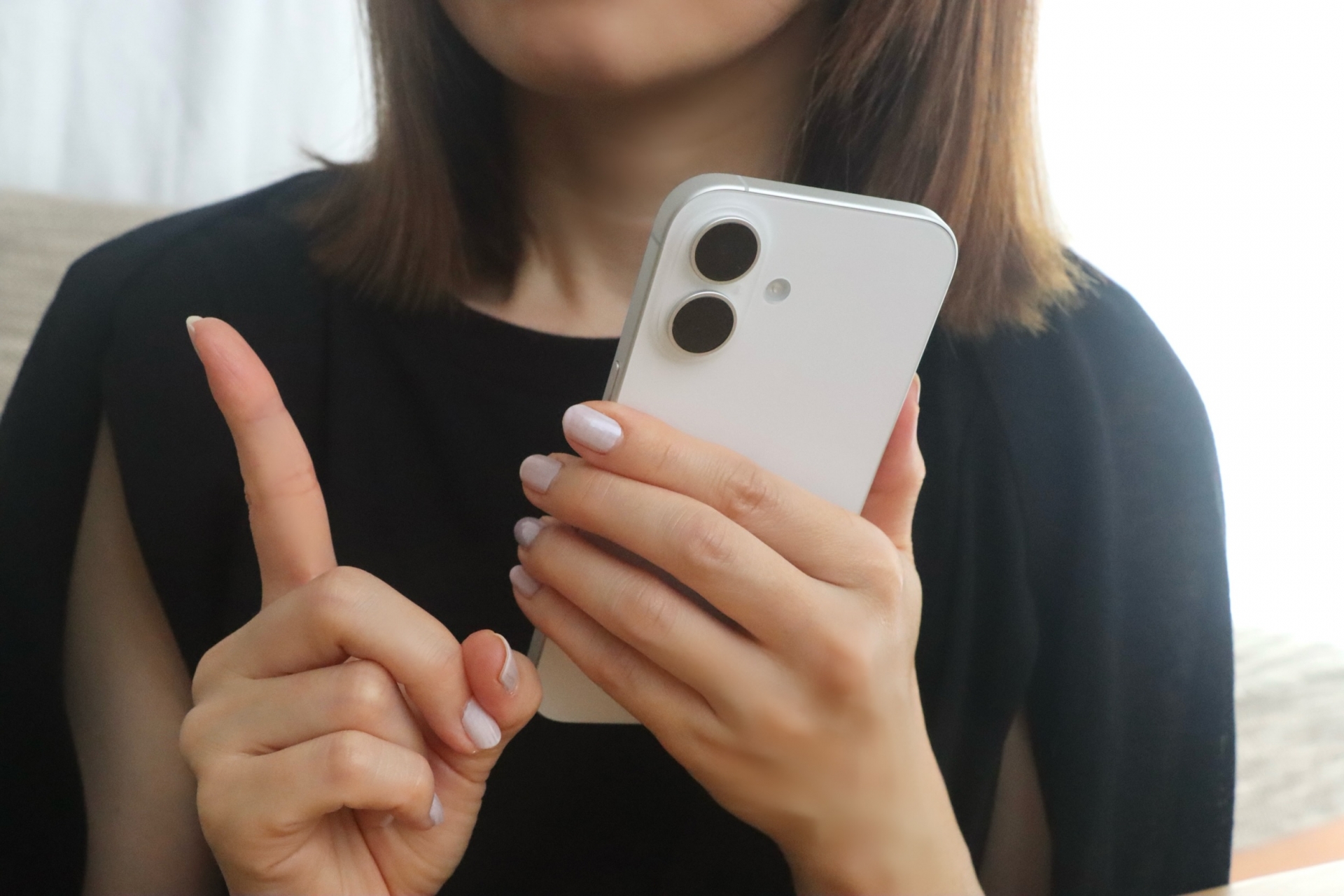スマホをもち指をさす女性