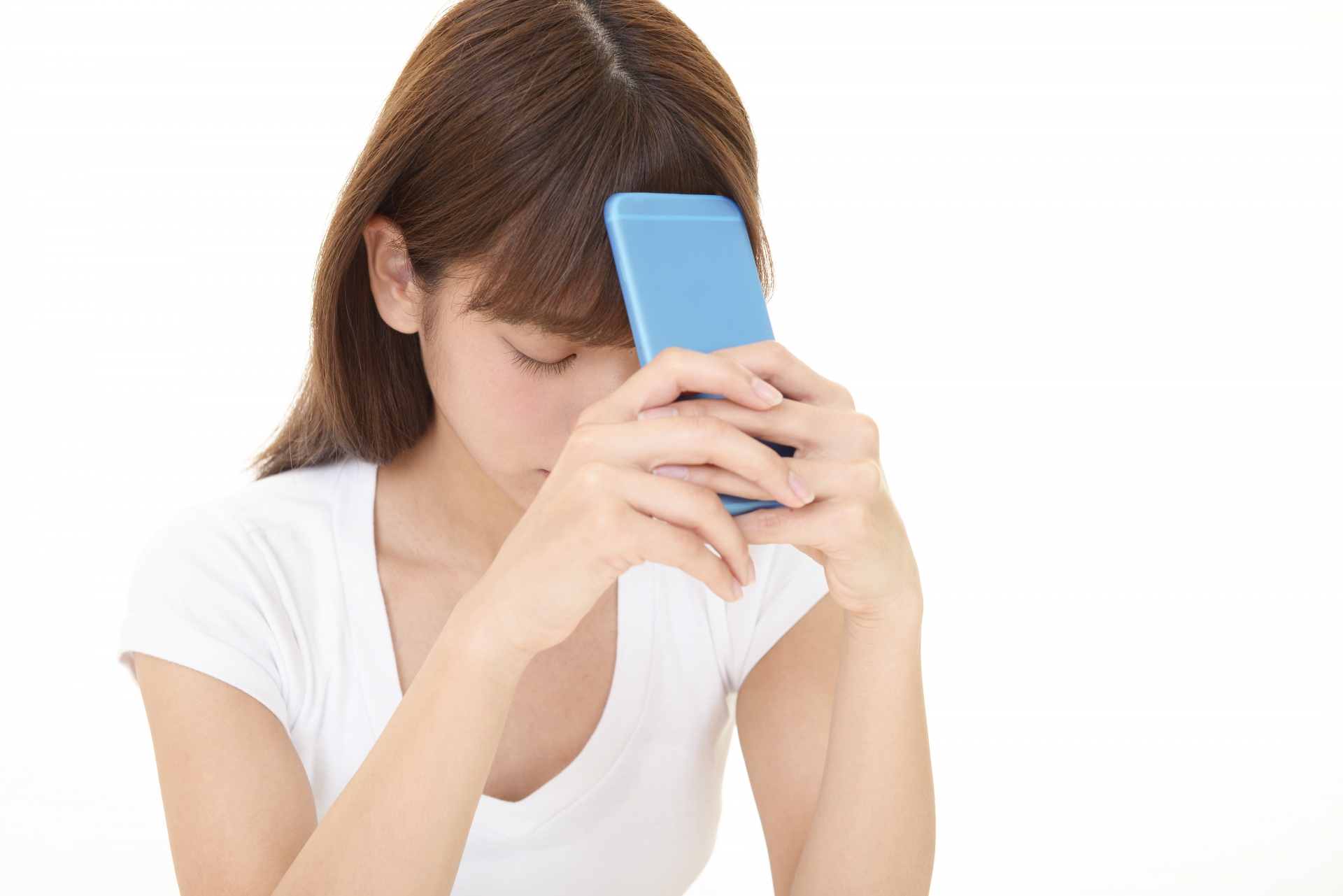 スマホを額に当てて悩む女性