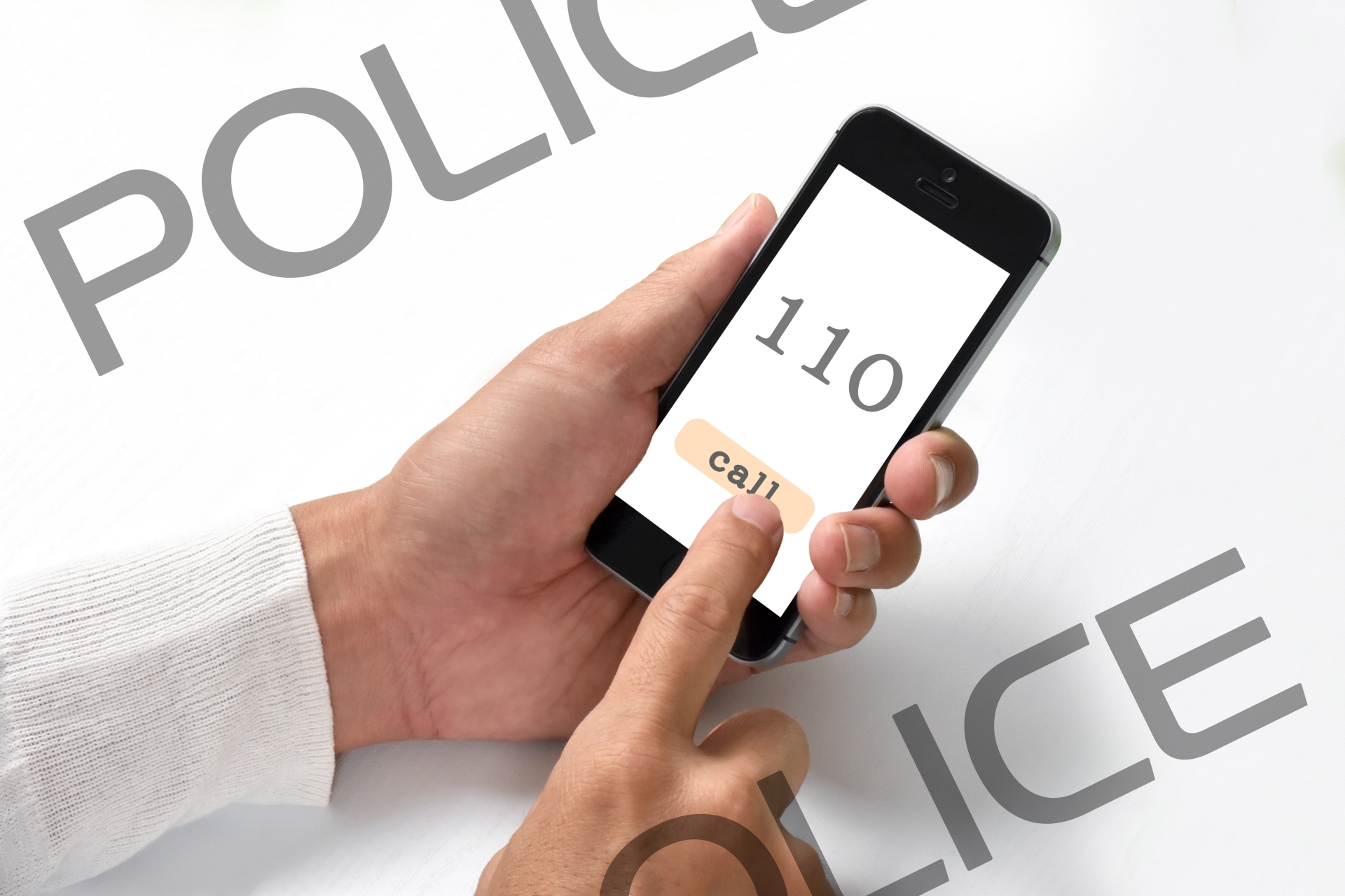 スマホで110番している手元