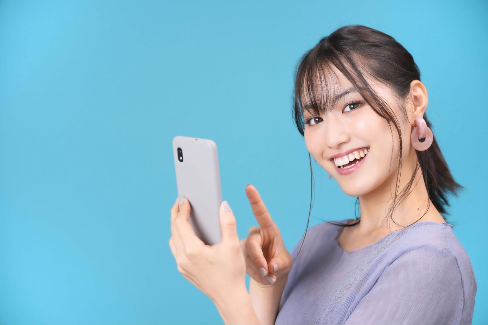 携帯電話を指さす女性
