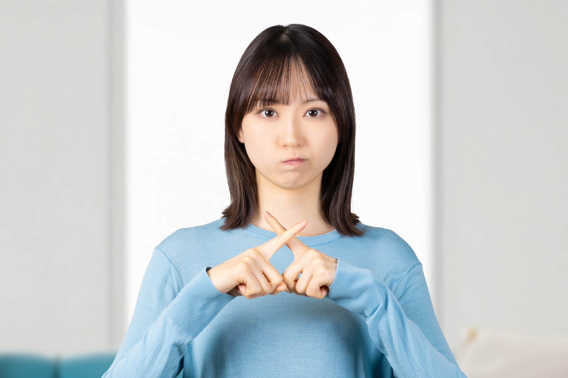 指でバツマークをする女性